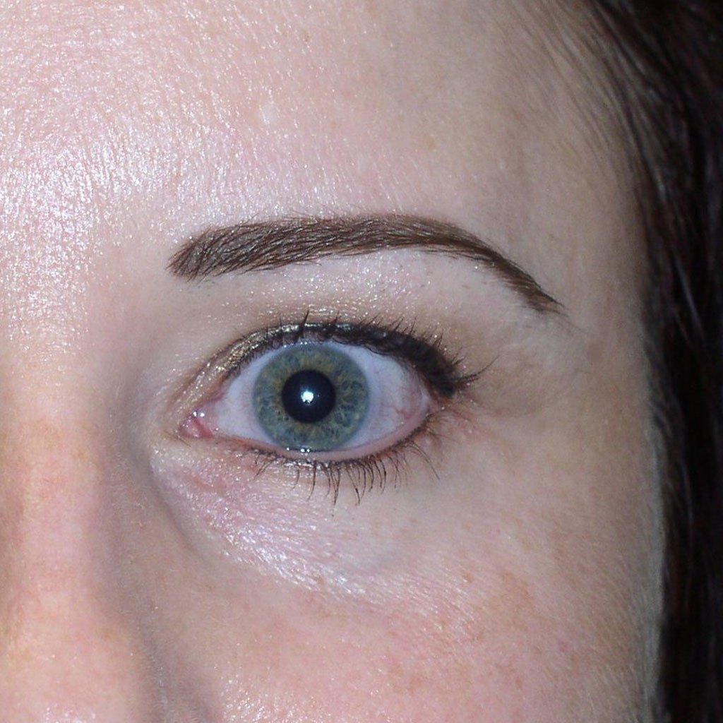 Close-up of brows shaded with Aqua Original Hazelnut pigment paired with Ebony Brown eyeliner, enhancing blue eyes. The healed result shows soft definition and balanced warmth, creating a natural yet polished permanent makeup effect.