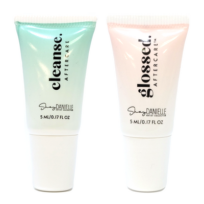 Two tubes of Shay Danielle Aftercare cleanser, one labeled 'CLEANSE' and the other 'GLOSSED AFTERCARE', each in different shades of mint green and pink respectively, both with product information and branding on the labels.