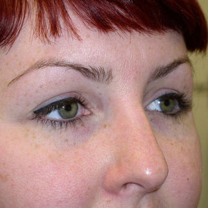 Healed permanent eyeliner results after first session, showing soft black lash line enhancement on green eyes with natural definition and even pigment retention.