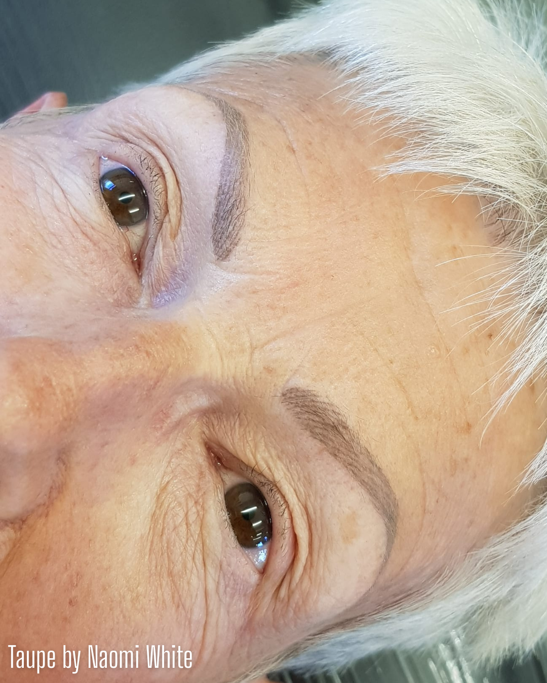 Close-up of healed eyebrows created with Taupe from the Li Pigments Aqua collection by Naomi White. The pigment delivers a soft ash-brown tone ideal for mature clients or those with gray hair, providing natural, balanced permanent makeup results that complement cool undertones.