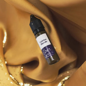 Hanafy Golden Blonde eyebrow pigment bottle on luxurious gold fabric with glitter detailing.