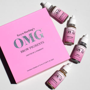 Flat lay of Teryn Darling’s OMG Brow Pigments crafted by Li Pigments, featuring a pink box and scattered bottles of PMU brow pigments on a white background.